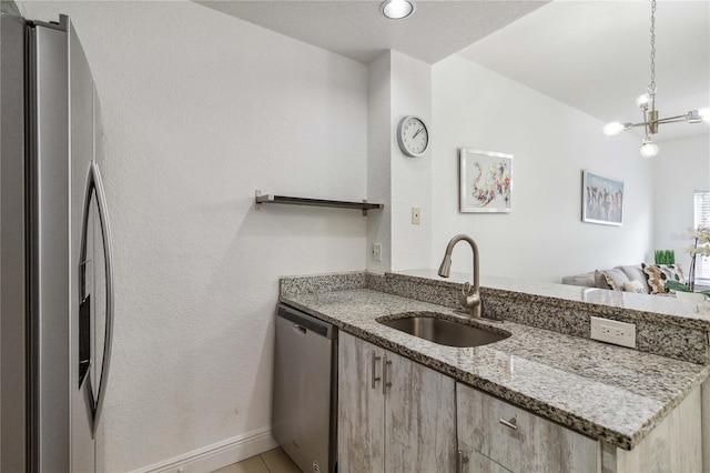 kitchen featuring decorative light fixtures, sink, light stone countertops, stainless steel appliances, and a chandelier