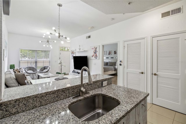 kitchen featuring decorative light fixtures, sink, stone countertops, a chandelier, and light tile patterned flooring