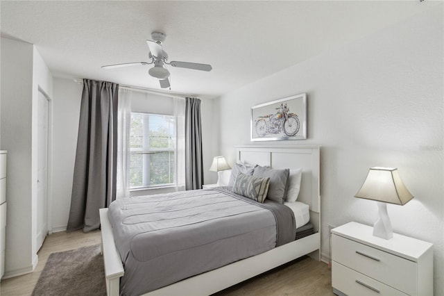 bedroom featuring ceiling fan, light hardwood / wood-style floors, and a textured ceiling