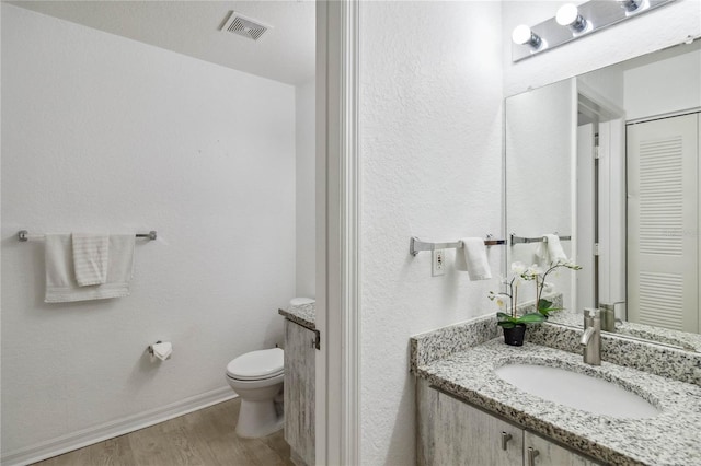 bathroom with hardwood / wood-style flooring, toilet, and vanity