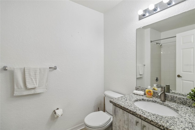 bathroom featuring toilet, vanity, and tiled shower