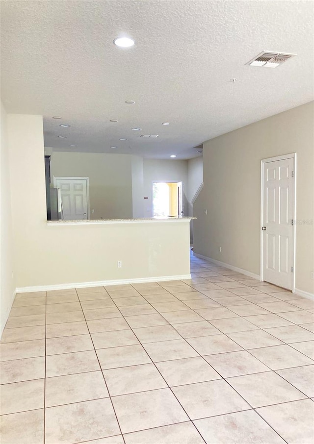 tiled empty room featuring a textured ceiling