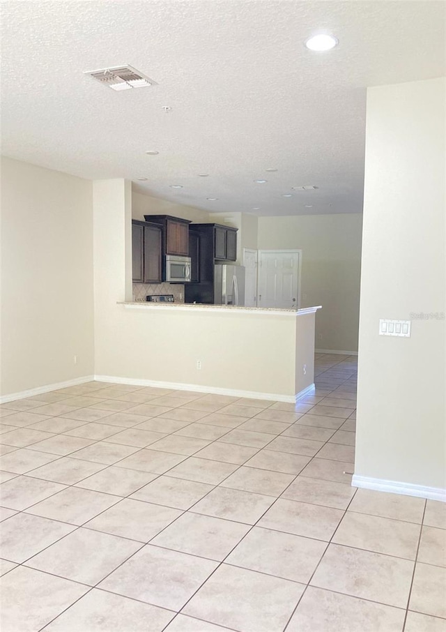 spare room featuring a textured ceiling and light tile floors