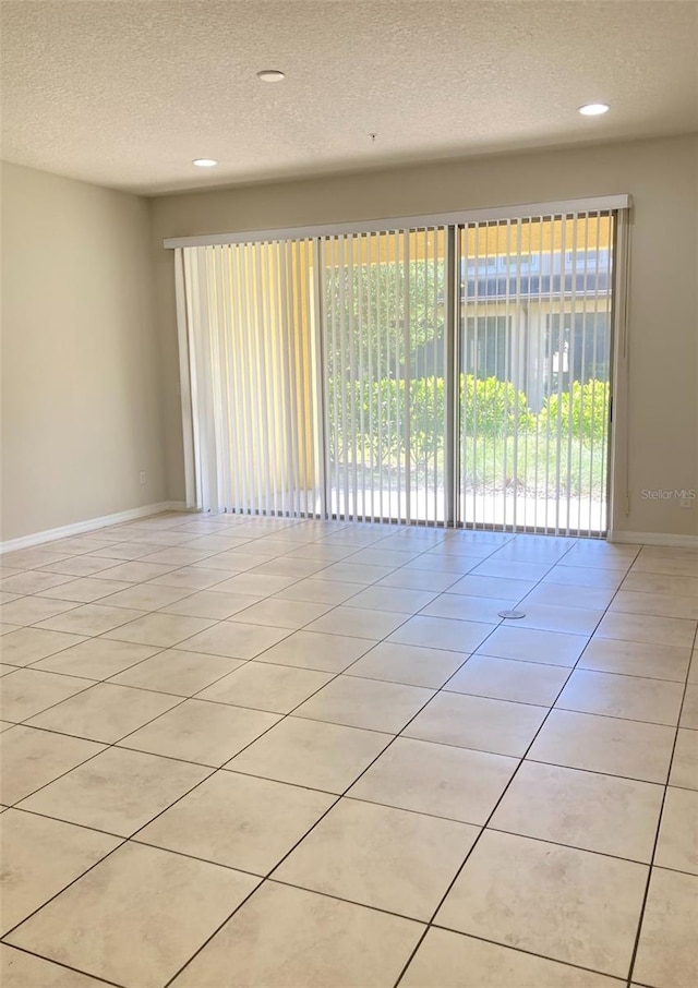 tiled empty room with a textured ceiling