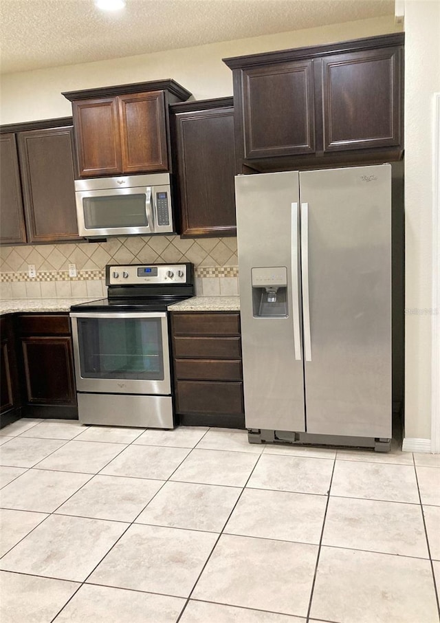 kitchen featuring backsplash, appliances with stainless steel finishes, and light tile flooring