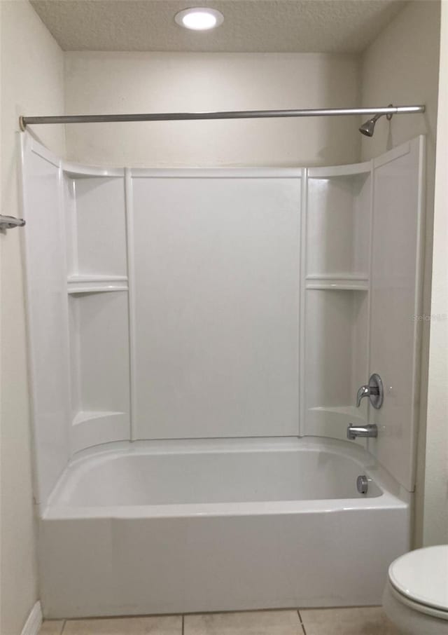 bathroom with tile flooring, a textured ceiling, toilet, and tub / shower combination