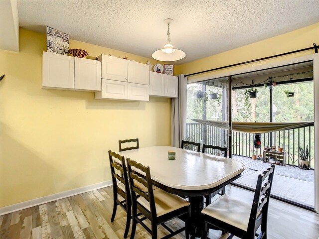 dining area with light hardwood / wood-style flooring and a textured ceiling