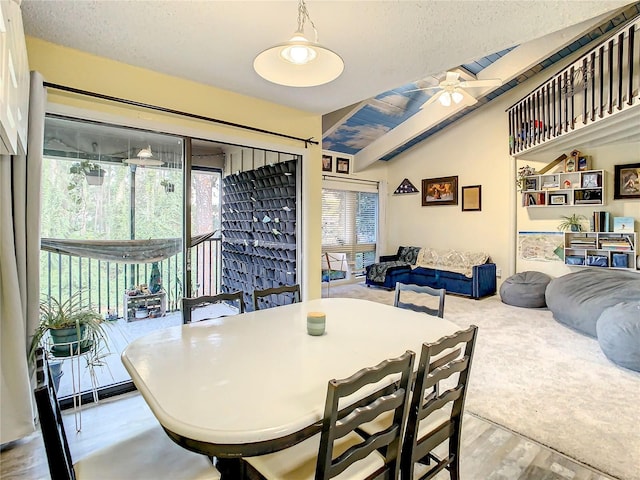 dining area featuring ceiling fan, lofted ceiling, a textured ceiling, and light hardwood / wood-style flooring