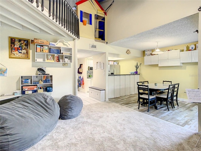 living room with a high ceiling, light hardwood / wood-style floors, and a textured ceiling