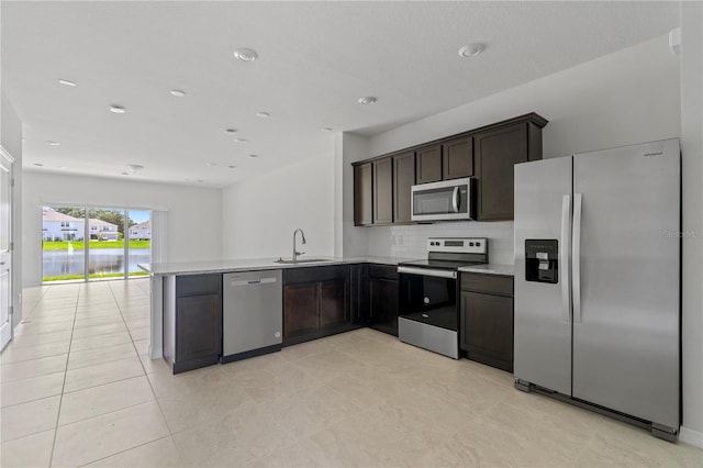 kitchen featuring kitchen peninsula, backsplash, dark brown cabinets, stainless steel appliances, and sink