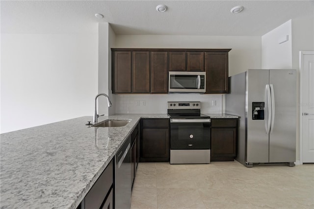 kitchen with sink, light stone counters, a textured ceiling, dark brown cabinets, and appliances with stainless steel finishes