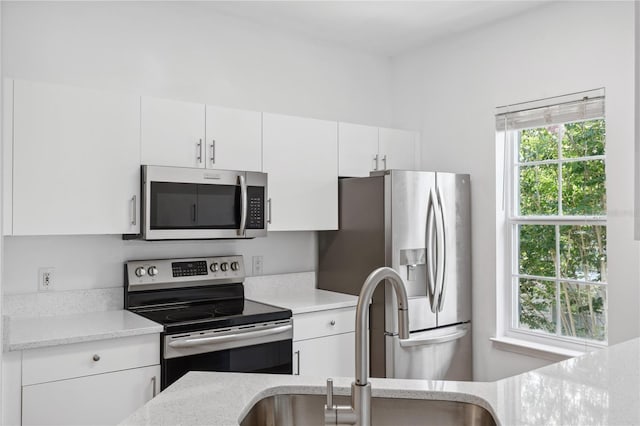 kitchen featuring white cabinets, light stone counters, sink, and appliances with stainless steel finishes