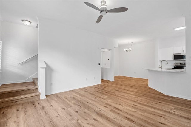 unfurnished living room with ceiling fan with notable chandelier, light hardwood / wood-style flooring, and sink