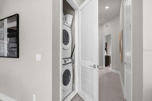 laundry room with light tile patterned flooring and stacked washer / dryer