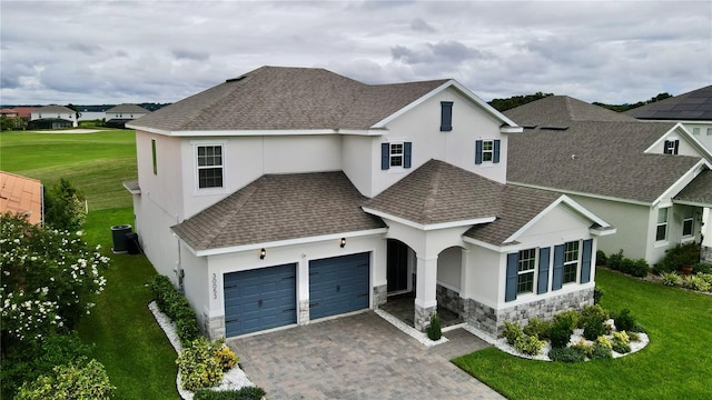 view of front of home with cooling unit, a garage, and a front lawn