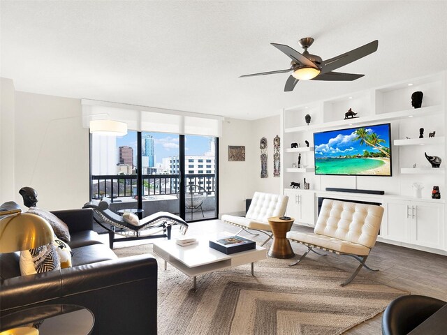 living room with built in features, hardwood / wood-style floors, and ceiling fan