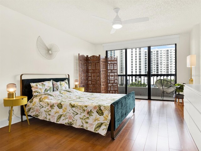 bedroom featuring ceiling fan, access to exterior, a textured ceiling, and dark hardwood / wood-style floors