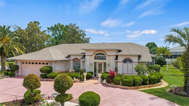 mediterranean / spanish home featuring a garage, french doors, and a front lawn