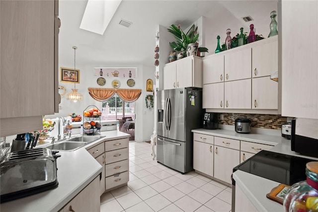 kitchen with sink, a skylight, hanging light fixtures, light tile patterned floors, and stainless steel fridge