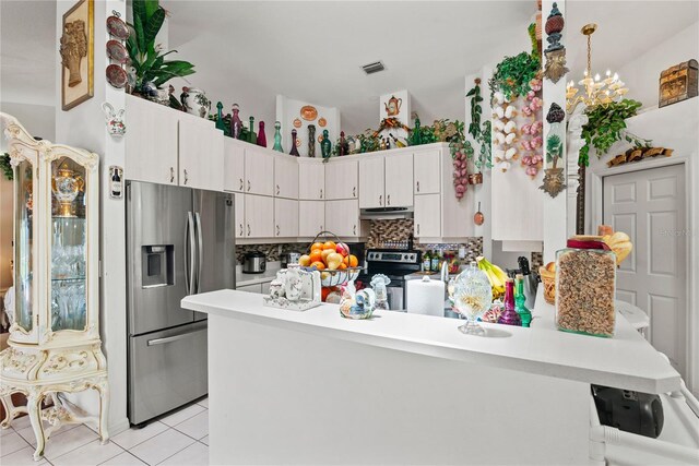 kitchen featuring appliances with stainless steel finishes, white cabinetry, tasteful backsplash, decorative light fixtures, and kitchen peninsula