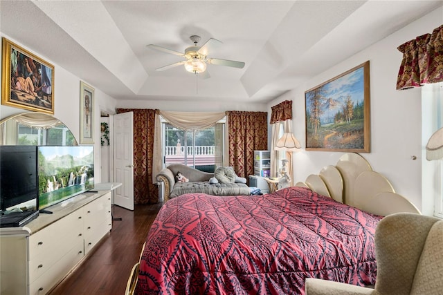 bedroom with dark hardwood / wood-style floors, ceiling fan, and a tray ceiling