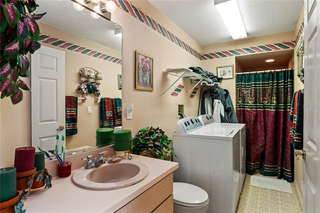 bathroom featuring vanity, a textured ceiling, washing machine and dryer, and toilet