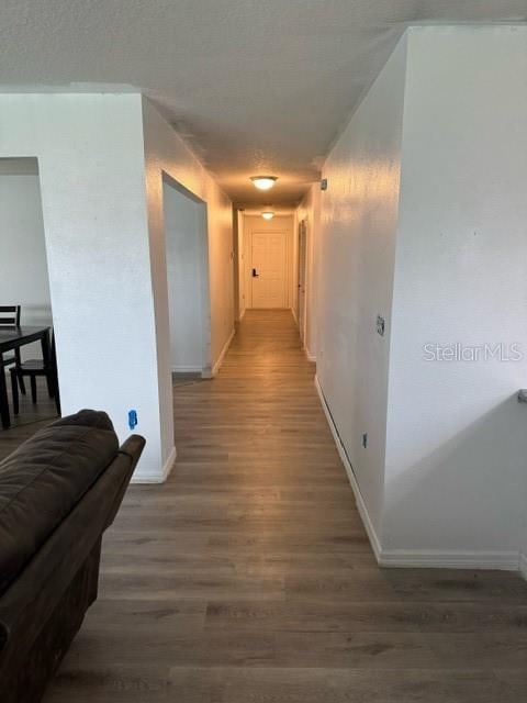 hallway featuring a textured ceiling and dark hardwood / wood-style floors