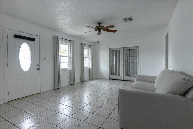 entryway with ceiling fan, light tile patterned flooring, and a textured ceiling