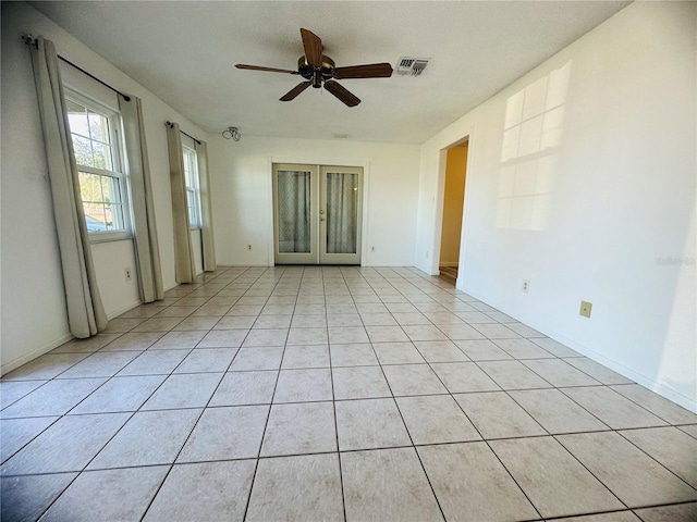 empty room with french doors, light tile patterned floors, and ceiling fan