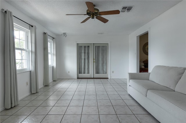 unfurnished living room with a textured ceiling, ceiling fan, and light tile patterned flooring