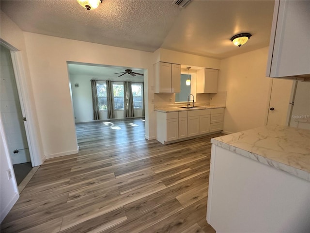 kitchen with white cabinets, a textured ceiling, hardwood / wood-style flooring, and sink