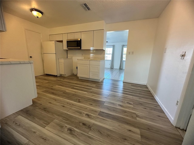 kitchen with white cabinets, white fridge, and dark wood-type flooring