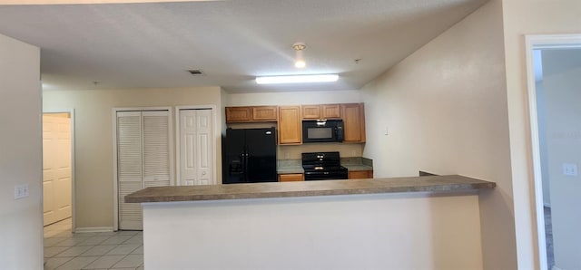 kitchen with black appliances, kitchen peninsula, a textured ceiling, and light tile patterned floors