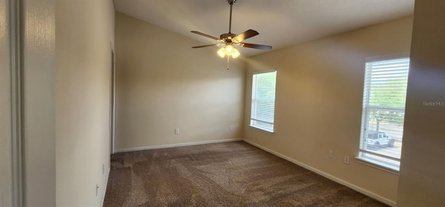 spare room featuring a healthy amount of sunlight, ceiling fan, and dark carpet