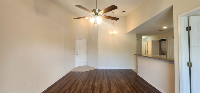 spare room with ceiling fan with notable chandelier, dark hardwood / wood-style floors, and high vaulted ceiling