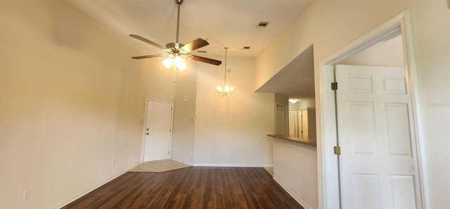 unfurnished living room with ceiling fan with notable chandelier, dark wood-type flooring, and high vaulted ceiling