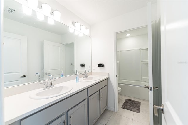 full bathroom with dual sinks, combined bath / shower with glass door, tile floors, toilet, and large vanity