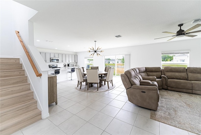 living room featuring light tile flooring, sink, plenty of natural light, and ceiling fan with notable chandelier