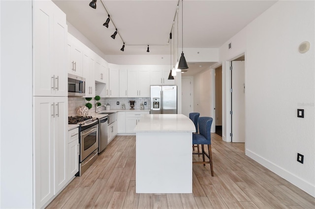 kitchen featuring a center island, light hardwood / wood-style flooring, appliances with stainless steel finishes, pendant lighting, and white cabinets