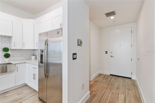 kitchen featuring sink, tasteful backsplash, stainless steel fridge with ice dispenser, light hardwood / wood-style floors, and white cabinets