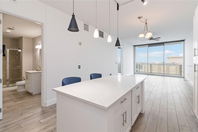 kitchen featuring pendant lighting, floor to ceiling windows, white cabinets, and a kitchen island