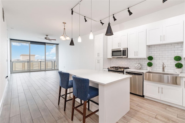 kitchen featuring a breakfast bar, sink, appliances with stainless steel finishes, decorative backsplash, and white cabinets