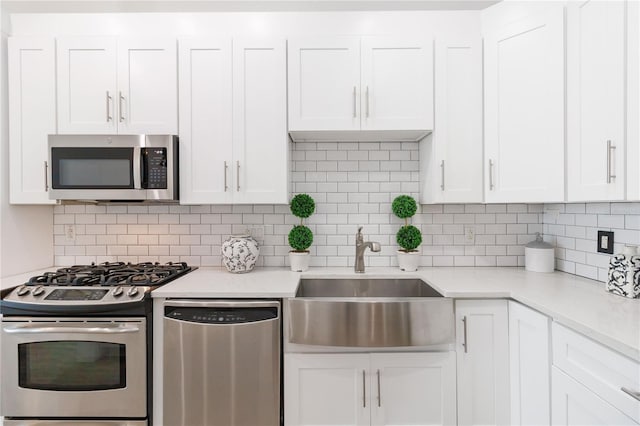 kitchen featuring stainless steel appliances, white cabinetry, sink, and decorative backsplash