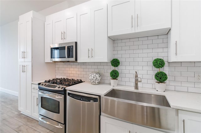 kitchen with stainless steel appliances, light stone countertops, white cabinets, and backsplash