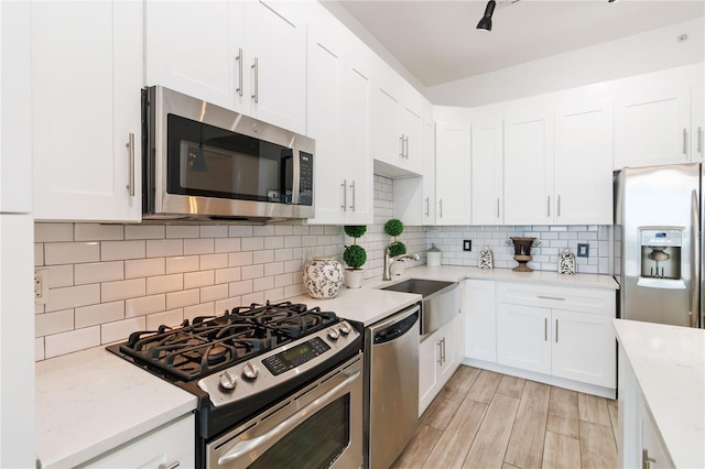 kitchen with tasteful backsplash, white cabinetry, appliances with stainless steel finishes, and sink