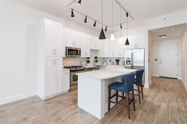 kitchen with a breakfast bar, appliances with stainless steel finishes, a kitchen island, pendant lighting, and white cabinets