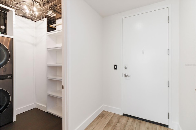 washroom featuring stacked washer and dryer and hardwood / wood-style flooring