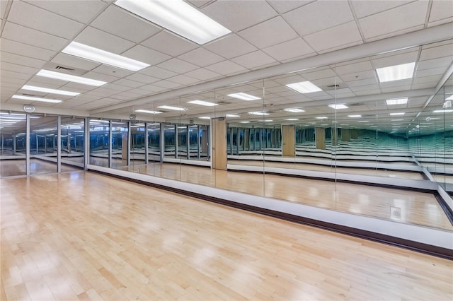 workout area featuring a paneled ceiling and wood-type flooring