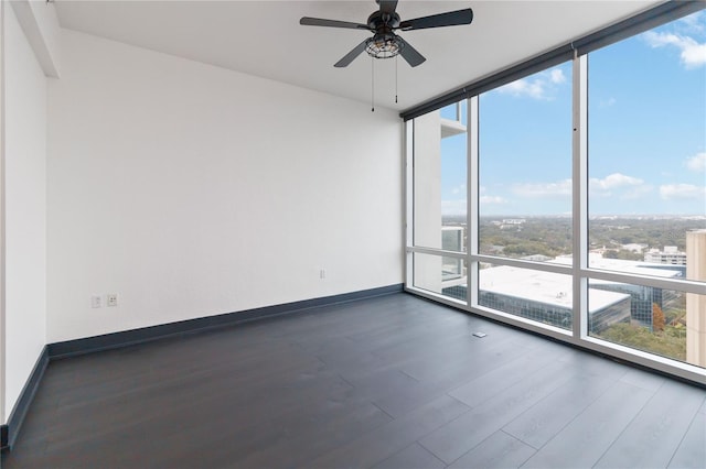 empty room with dark hardwood / wood-style flooring, floor to ceiling windows, and ceiling fan