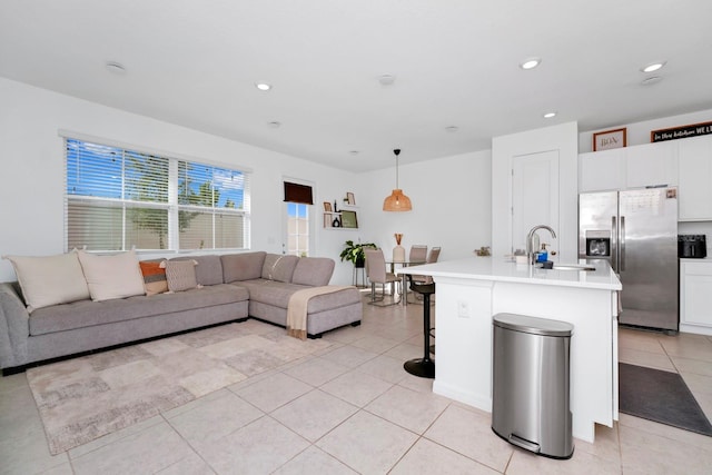 kitchen with stainless steel fridge with ice dispenser, hanging light fixtures, a center island with sink, a breakfast bar area, and sink